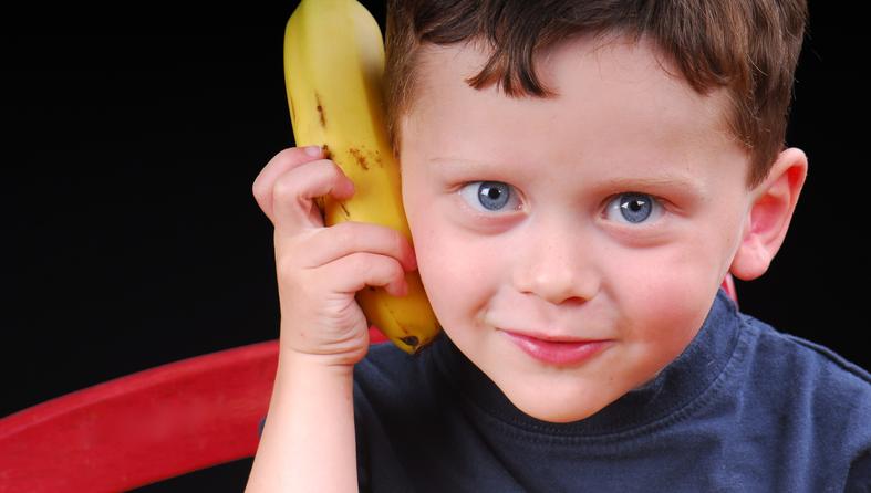 dječak drži bananu na uhu