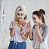 Two twins girls in pajamas with facial mask and cucumber slices.