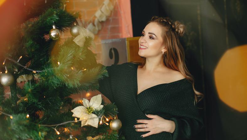Elegant young lady sitting near Christmas tree