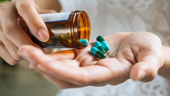 Woman's hand pours the medicine pills out of the bottle