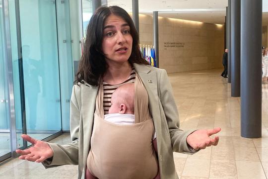 Swedish Environment Minister Romina Pourmokhtari, carrying her baby Adam, speaks to journalists before a meeting of EU environment and climate ministers, in Luxembourg