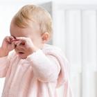 Tired baby girl crying and rubbing her eyes